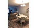 Open floor plan living room and dining room features wood-look flooring and modern chandelier at 860 Virginia St # 308, Dunedin, FL 34698