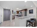 Modern kitchen featuring granite countertops, stainless steel appliances, breakfast bar, and tile flooring at 12900 Vonn Rd # F101, Largo, FL 33774