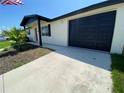 Close up of the exterior of the home including the black garage door, and walkway at 12907 College Hill Dr, Hudson, FL 34667