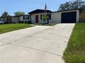 Charming single-story home featuring a red front door, well-manicured lawn, and a long driveway leading to the garage at 12907 College Hill Dr, Hudson, FL 34667