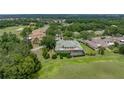 An elevated aerial of the home with a screened-in lanai, green roof, landscaping, and golf course views at 13209 Palmilla Cir, Dade City, FL 33525