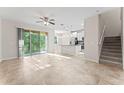 Bright living room area opens to a modern kitchen, featuring sleek tile floors and a staircase at 13233 Canopy Creek Dr, Tampa, FL 33625