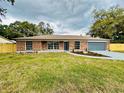 Charming brick home featuring a well-manicured front yard and a freshly painted driveway and garage door at 15307 Stonecreek Ln, Tampa, FL 33613