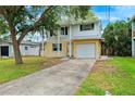Two-story home with white and yellow siding, green shutters, attached garage, mature tree, and concrete driveway at 1810 Maryland Ne Ave, St Petersburg, FL 33703