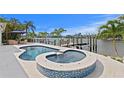 A gorgeous pool and jacuzzi overlook the waterfront, with ample space for entertaining at 243 Hermosita Dr, St Pete Beach, FL 33706