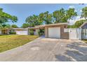 Charming exterior view of home, featuring a long driveway, lush lawn, and an attached single-car garage at 2933 Stratford Dr, Largo, FL 33771