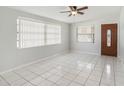 Bright living room featuring tile flooring, a ceiling fan, large windows, and a wooden front door at 3308 W Walnut St, Tampa, FL 33607
