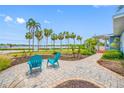Charming front yard with blue Adirondack chairs, brick pavers, lush landscaping, and picturesque water views lined with palm trees at 401 Whitcomb Blvd, Tarpon Springs, FL 34689