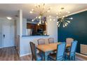 Elegant dining area with modern lighting, a wooden table, and stylish chairs set against a blue accent wall at 4221 W Spruce St # 1303, Tampa, FL 33607