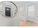 Bright entryway with light hardwood floors, an oval mirror, and white doors with black handles at 4911 N Nebraska Ave, Tampa, FL 33603