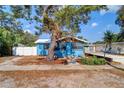 Quaint blue bungalow with mature trees, a white fence, and a welcoming front yard at 520 4Th Nw St, Largo, FL 33770
