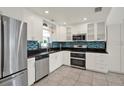 Modern kitchen boasts stainless steel appliances, stylish backsplash, and white cabinetry at 5875 Darren N Ct, Clearwater, FL 33760