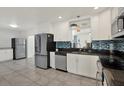 Bright kitchen featuring stainless steel appliances, white cabinets, and a blue backsplash at 5875 Darren N Ct, Clearwater, FL 33760