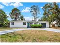Beautiful single-story home with a gray driveway, lush landscaping, and a sleek gray garage door at 6120 5Th N Ave, St Petersburg, FL 33710