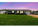 Well-maintained single-story home with a green lawn and beautiful twilight sky at 6246 Bandura Ave, New Port Richey, FL 34653
