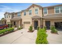 Tan townhome with a one-car garage, green bushes and well maintained driveway and a parked car at 6912 40Th N Ln, Pinellas Park, FL 33781