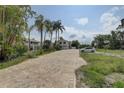 Property featuring a brick driveway leading up to a two-story home surrounded by palm trees at 8117 Bay Dr, Tampa, FL 33635