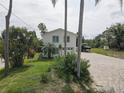 Exterior of a two-story home featuring a brick driveway and tropical landscaping at 8117 Bay Dr, Tampa, FL 33635