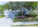 Quaint single-story home with mature trees, garden beds, and a two car garage at 9220 Dayflower Dr, Tampa, FL 33647