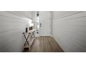 Bright hallway featuring wood-look floors, stylish white wainscoting, and an elegant accent table at 923 Whimbrel Run, Bradenton, FL 34212