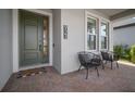 Inviting porch with a green door, brick pavers, modern outdoor chairs and the house number at 923 Whimbrel Run, Bradenton, FL 34212