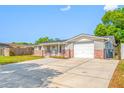 Inviting home featuring a gray facade with brick accents, a garage, and a long driveway at 10825 Oakdale Ave, Port Richey, FL 34668