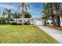 Charming single-story home with a well-manicured lawn, palm trees, and a one-car garage at 119 N Hillcrest Ave, Clearwater, FL 33755