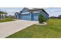 Three car garage of a blue single story home with a green lawn at 12710 Wheatgrass Ct, Parrish, FL 34219