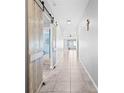 Bright hallway featuring a barn door, leading to a living space, and neutral tile flooring at 15507 Caynor Ash Ln, Sun City Center, FL 33573
