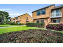 Complex exterior view showcasing green lawn and landscaping in front of multiple stucco-covered townhouses at 1864 Clearbrooke Dr, Clearwater, FL 33760