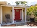 Close-up of the front entryway, showcasing a red front door with a decorative glass window and rocking chairs at 1891 Harmony Dr, Clearwater, FL 33756