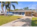 Cozy home with a well-kept lawn, blue accents, and a carport for convenient parking at 306 12Th Ave, Indian Rocks Beach, FL 33785