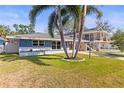 Quaint single-story home with a lush green lawn, palm trees, and a welcoming front entrance at 306 12Th Ave, Indian Rocks Beach, FL 33785