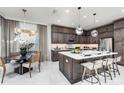 Elegant kitchen featuring dark wood cabinetry, a center island with seating, and adjacent dining area at 32523 Neroli St, Wesley Chapel, FL 33543