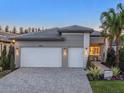 Stylish home with a two-car garage, stone accents, a paved driveway, and manicured landscaping at 32608 Neroli St, Wesley Chapel, FL 33543