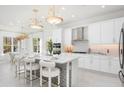 Bright, modern kitchen featuring white cabinets, stainless steel appliances, and a spacious island with seating at 32608 Neroli St, Wesley Chapel, FL 33543