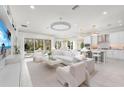 Open-concept living space with sleek furniture, abundant natural light, and a modern kitchen in the background at 32608 Neroli St, Wesley Chapel, FL 33543