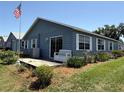 Back of home with sliding glass doors, landscaping, white bench, and an American flag at 37401 Teaberry Loop, Zephyrhills, FL 33542