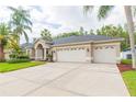 Attractive home exterior with lush lawn, concrete driveway leading to a three-car garage, and lovely landscaping at 10002 Colonnade Dr, Tampa, FL 33647