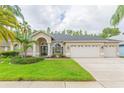 Beautiful exterior of a home featuring lush green lawn, mature palm trees, and a spacious three-car garage at 10002 Colonnade Dr, Tampa, FL 33647