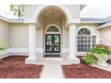 Elegant front entrance with double doors framed by columns and an arched entryway, complemented by lush landscaping at 10002 Colonnade Dr, Tampa, FL 33647