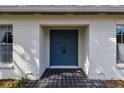 Close up view of the house's blue double door entryway with black tiled porch and white brick walls at 103 Hickory Creek Blvd, Brandon, FL 33511