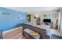 Cozy living area with stylish blue accent wall, wood floors, large sectional, and natural light at 1433 Spring Ln, Clearwater, FL 33755