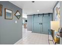 Hallway featuring elegant mirrors, white tile floors, and sliding barn doors to living area at 1480 Gulf Blvd # 1004, Clearwater Beach, FL 33767