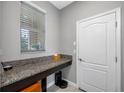Functional laundry room with granite countertop, storage space, and a window for natural light at 1811 Redmond Brook Ln, Ruskin, FL 33570