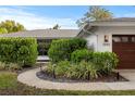 Exterior view of home with walkway, lush shrubbery, and two-car garage at 2665 Clubhouse N Dr, Clearwater, FL 33761