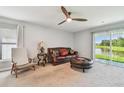 Bright living room with plush carpeting, ceiling fan, and sliding glass doors to the backyard at 36673 Spanish Rose Dr, Dade City, FL 33525