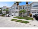 Gray two-story townhome featuring a white garage door and manicured landscaping at 568 Shoreham Ne Ct, St Petersburg, FL 33716