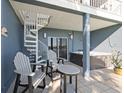 Relaxing covered patio with a hot tub, chairs, spiral staircase, and tranquil waterfront views at 9939 1St E St, Treasure Island, FL 33706
