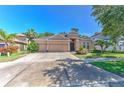 Inviting single-story tan home with a lush lawn, palm trees and a wide driveway leading to a three-car garage at 10212 Holland Rd, Riverview, FL 33578